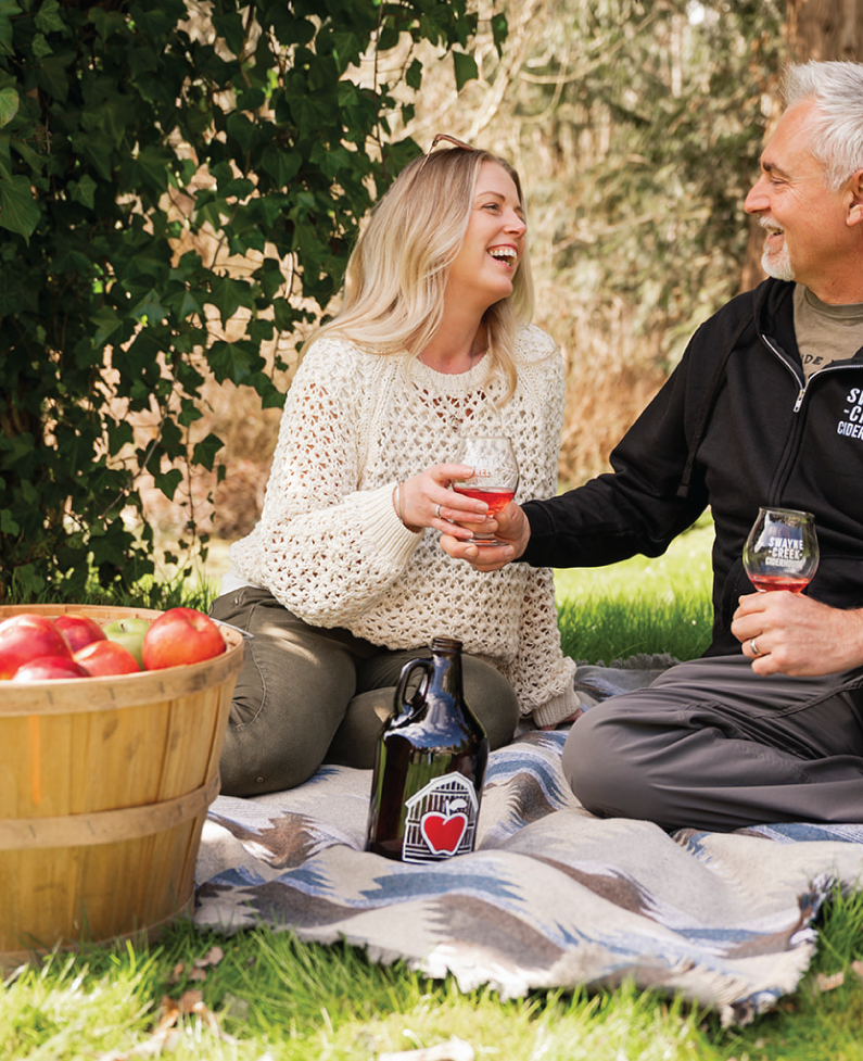LP_friends Couple sitting on a blanket at Swayne Creek Cider House, enjoying cider together outdoors.