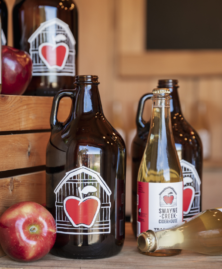 Bottles of Swayne Creek Cider and ripe apples